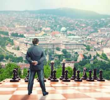 Businessman standing in front of the black team on the chess board 