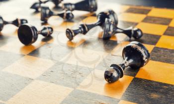 Old wood chess figures lying on the board defeated