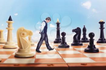 Businessman is walking on the chess board thinking