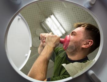 Man cleaning the toilet with cup plunger