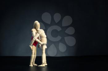 Couple of wooden figures hugging in dark