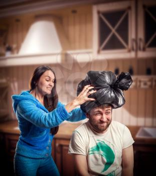 Angry wife putting trash pack on her husband head in the kitchen