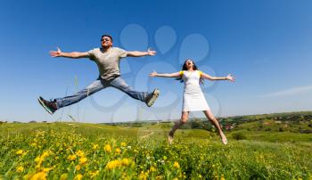 Happy young couple jumping high on the summer meadow