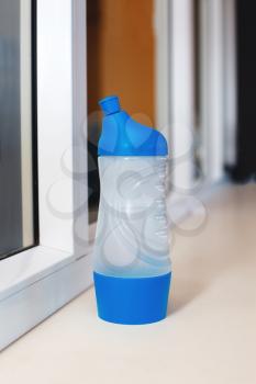 Blue sport bottle standing on the windowstool