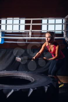 Woman exercising with hammer and a big wheel