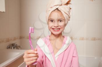 Little girl with toothbrush in hand in  bathroom.