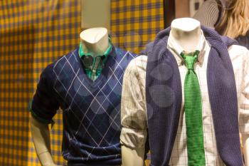 Male mannequins in modern youth clothes in showcase of shop store.