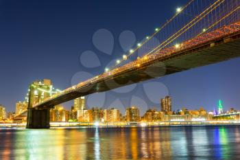 Illuminated Brooklyn bridge and manhattan view from hudson river at night time, New York City USA