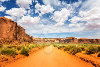 Sand road along red sandstone mountains at Monument Valley National Tribal Park, Navajo, Utah USA