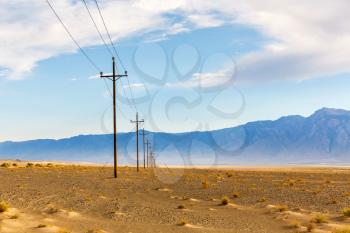 Power line in desert with mountains on background at Death Valley National Park, California, USA