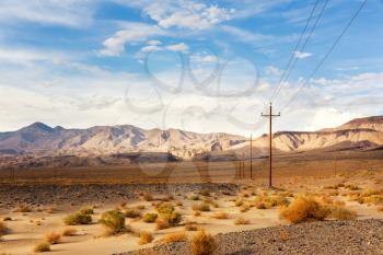 Power line in desert with mountains on background at Death Valley National Park, California, USA