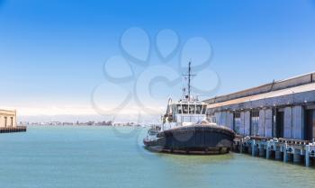 Tow ship is in the harbor of seaport. Tugboat in port.