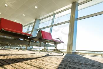 Airport, bus or train station with red chairs against glassed wall. Travel or tourism concept.