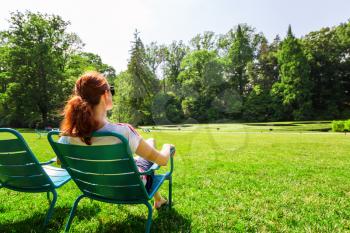 Young woman in eyeglasses relax on greenfield in sunny day.