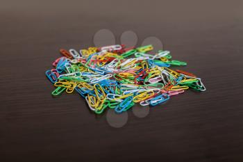 Colorful paper clips isolated on wooden background. Office color paperclip