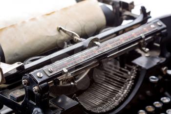 Vintage typewriter ribbon mechanism with inserted old paper closeup.