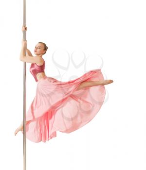 Young slim poledance woman posing in beautiful pink dress. Professional strip dancer exercising with pole in dance studio