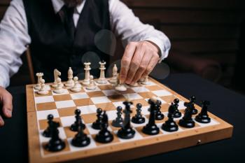 Serious male chess player in glasses makes victory move. Win strategy concept