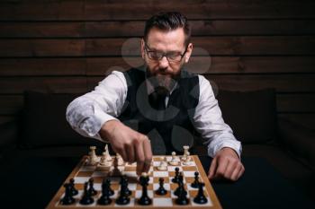 Serious male chess player in glasses makes victory move. Win strategy concept