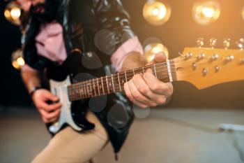 Male guitarist hands performing music on the stage with the decorations of lights. Musical solo concert