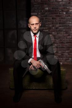 Contract killer wallpaper, background or poster concept. Assassin in suit and red tie holding pistol in hand