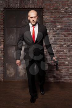 Contract murderer wallpaper, background or poster concept. Assassin in suit and red tie holding pistols in hands