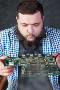 Male computer engineer blows off the dust from motherboard. Electronic devices repairing technology and service support