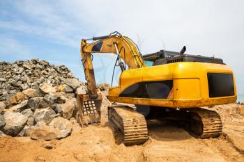 Excavation mashine works in a quarry. Yellow earth mover digging sand