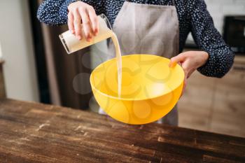 Female person adds cream into a bowl, homemade cake cooking. Fresh tasty dough preparation