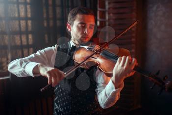 Male violinist playing classical music on violin. Fiddler man with musical instrument