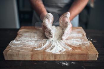 Male baker hands kneading dough on cutting board. Bread preparation. Homemade bakery