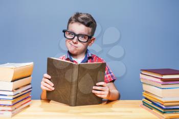 Young pupil in glasses reading a book in the school library. Education concept