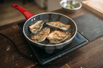 Frying pan with fried fish fillet, seafood cooking. Sea bass slices
