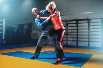 Woman fights with man on self-defense training, fighting workout in gym, martial art