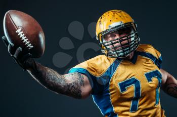 American football offensive player with ball in hand, national league, black background. Contact sport