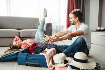 Young couple packing their suitcases for vacation. Fees on journey concept. Luggage preparation