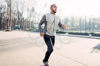 Male jogger in motion, running in autumn park, healthy lifestyle. Athlete on morning fitness workout. Runner in sportswear on training outdoor