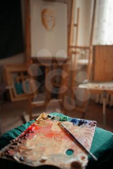 Color palette and brush closeup, easel on background, nobody, paintbrush art drawing. Artist workshop interior, painter tools and equipment, painting supplies