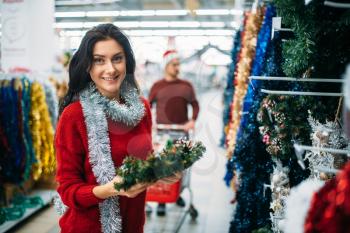 Young couple purchasing christmas holiday decorations in supermarket, family tradition. December shopping