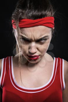 Serious female kickboxer in red gloves and sportswear, black background. Woman on boxing workout