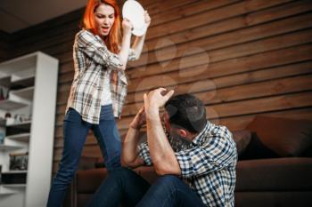 Angry woman breaking dishes, family quarrel, agressive girl. Husband and wife in conflict. Problem relationship