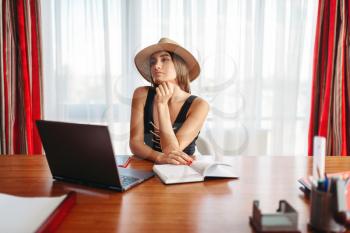 Young businesswoman sitting at the table in office and dreaming about a vacation