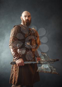 Angry viking with axe, martial spirit, barbarian image. Ancient warrior in smoke closeup