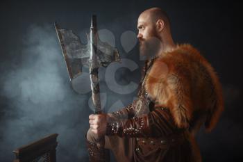 Viking with axe, martial spirit, barbarian image, side view. Ancient warrior in smoke on dark background