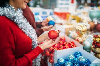 Female person buying christmas tree balls in supermarket, family tradition. December shopping of holiday goods