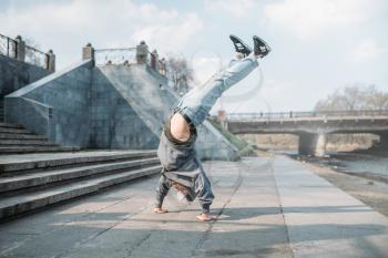 Breakdance performer, upside down motion on the street. Modern dance style. Male dancer