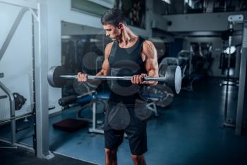 Tanned muscular man workout with barbell in gym. Active training in sport club