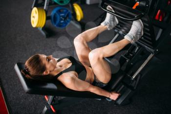 Young woman in sportswear trains on exercise machine in sport gym.  Female athlete workout in fitness club