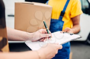 Male worker in uniform gives a parcel to the client, distribution business. Cargo delivery. Empty container