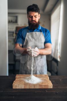Male chef in apron with flour in hands working on cutting board. Bread cooking